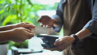 a person tapping credit card on a touch-to-pay device