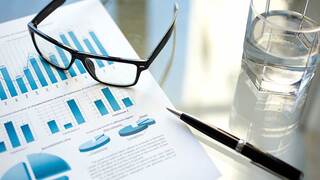 glasses sitting on a book open to a page with bar graphs with a glass of water and pen